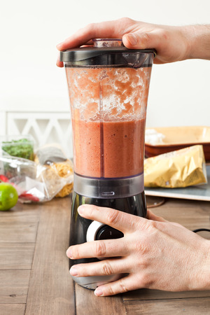 A chef's hands operating an electric food blenderの写真素材