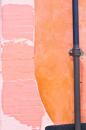 A drain pipe on an external wall with  painted shades of color