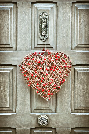 A heart shaped christmas wreath on a wooden front doorの写真素材
