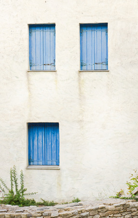 White wall of a greek house with blue shuttersの写真素材