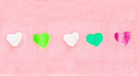 Row of colorful painted heart shapes on a pick wall