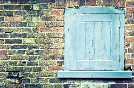 A blue shutter in a red brick wall