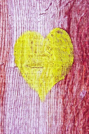 Yellow painted heart on a wooden surfaceの写真素材