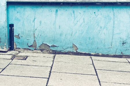 A weathered blue wall and a sloping pavementの写真素材