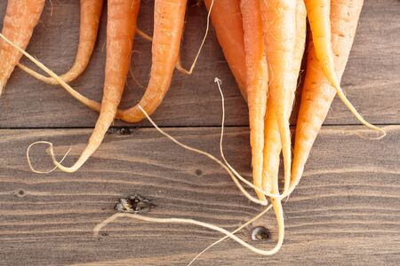 Tips of freshly harvested carrots on a wooden surfaceの写真素材