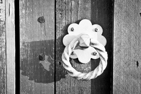 A metal knocker on a wooden gate in black and whiteの写真素材