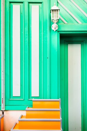 Orange portable steps outside a house with green and white panelsの写真素材