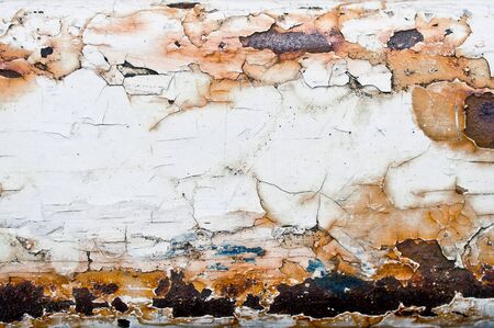 Cracked white paint on a rusty metal surface with selective focusの写真素材