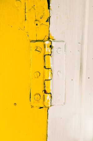 A yellow and white hinge with adjoining wood panels