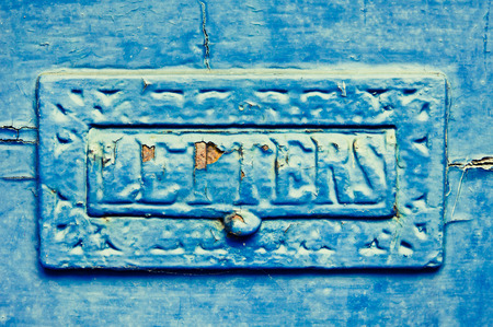 An old metal letterbox painted blue with peeling paint and rustの写真素材