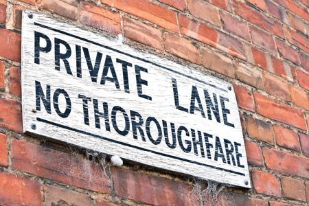 A white wooden sign for a private lane, on a brick wallの写真素材