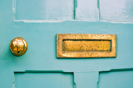 Part of a blue front door with a weathered metal letterboxの写真素材