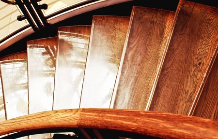 Part of an interior wooden staircase, in warm tones