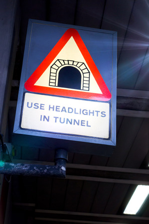 A warning sign in a tunnel instructing drivers to use headlightsの写真素材