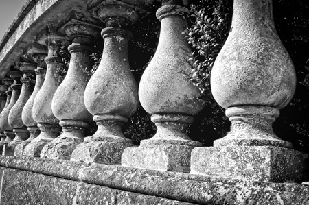 Part of a curved stone wall with balsutrade pillars, in black and white tones