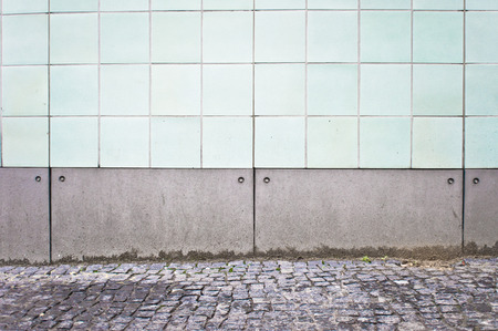 Part of a white tiled wall on the exterior of an urban buildingの写真素材