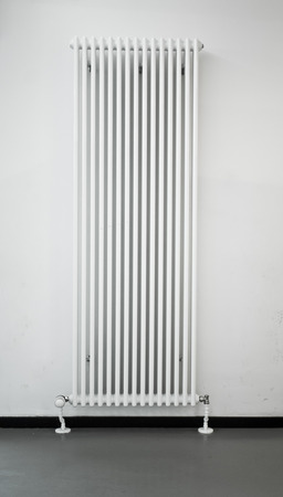 A tall white radiator against a white wallの写真素材