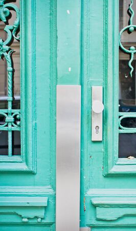 Part of a locked turquoise door with decorative bars