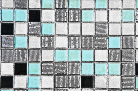 A wall of old blue, white,grey and black tiles as a background image