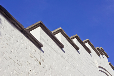 Part of a white wall on a 1930s art deco building against a blue skyの写真素材