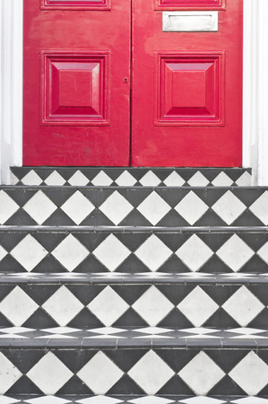 Tiles steps at the entrance of a house with a red door