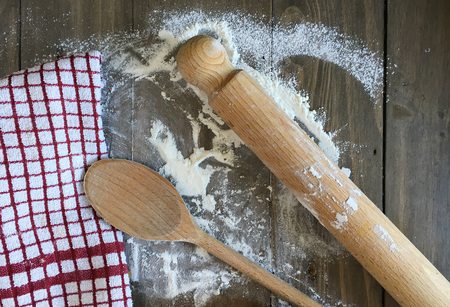 Wooden utensils and a tea towel on a flour covered wooden surface