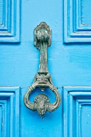 An antique metal knocker on a blue wooden doorの写真素材