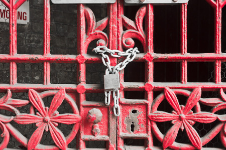 A red metal gate locked with a chain and padlockの写真素材