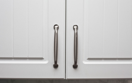 Chrome handles on a pair of wooden cupboard doorsの写真素材