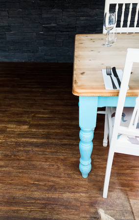 The end of a wooden dining table with colorful legs