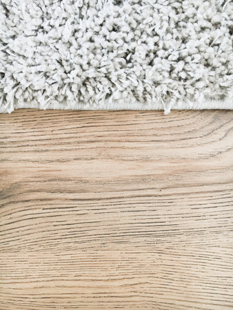 The edge of a long pile white rug on a wooden laminate floorの写真素材