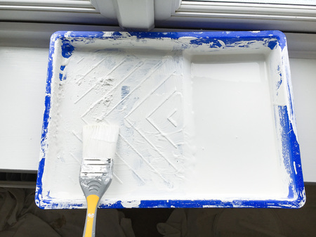 A used brush in a tray of white paint