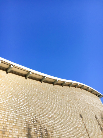 Part of the exterior of a modern brick building against a clear blue skyの写真素材