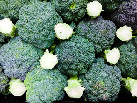 Stacked fresh broccoli for sale at a marketの写真素材