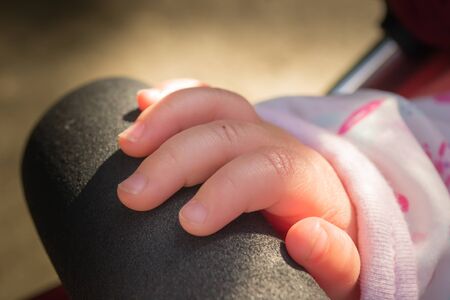 A babies hand resting on the bar across a pushchair in the united kingdomの写真素材