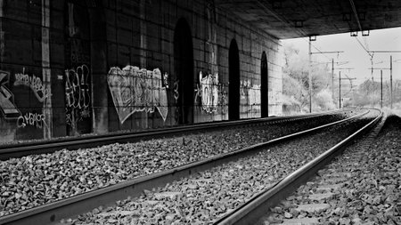 Railroad tracks in the tunnel under the highway in black and white styleの写真素材