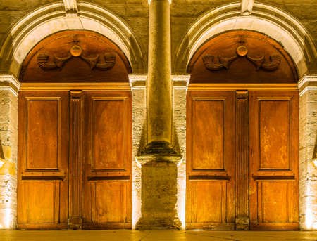 The great old wooden door to the church, illuminated at nightの写真素材