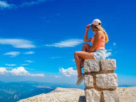 Young girl sitting on a stone with a beautiful view from the top of Mont Ventouxの写真素材