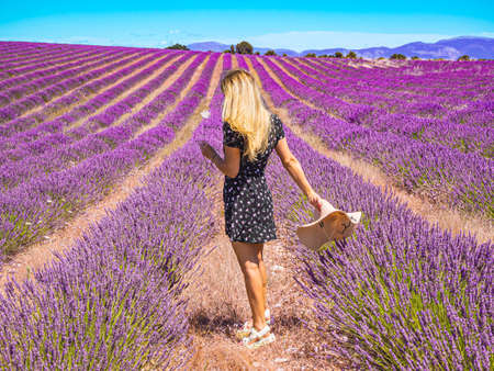 Close up of a young girl in a floral dress with a hat on her head between lavender in southern Provence Valensole Franceの写真素材