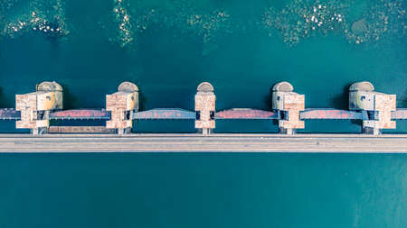 Top view of the dam, drainage of water through locks, industrial concept banner in blue. Visible river bed with huge stonesの写真素材
