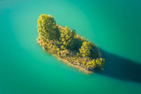 Small islet in the middle of a turquoise lake overgrown with vegetationの写真素材