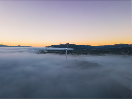 Panoramic view of wind farms in heavy fog in the morning during the rising sunの写真素材