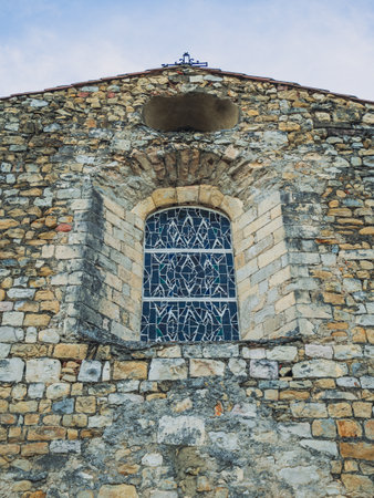 A small window with a stained glass window in an old stone churchの写真素材