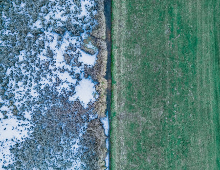 Aerial view of a frozen lake. Ice sheet background. Frozen grass on the lake. ice background. Ice cover on a lake. Aerial view of frozen lake and shore covered with green grassの写真素材