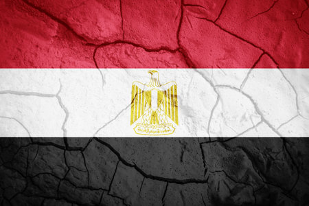Flag of Egypt. Symbol of Egypt. Flag on the background of dry cracked earth. Egyptian flag with drought conceptの写真素材
