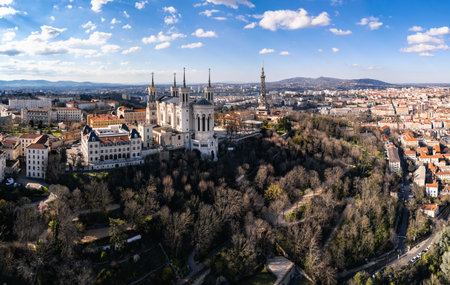 Aerial panoramic view of the Basilica of Notre-Dame de FourviÃ¨re on FourviÃ¨re Hill in Lyon, France, with cityscape and metallic tower in the background on a clear sunny dayの写真素材