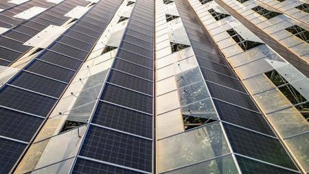 Sustainable greenhouse with rooftop solar panels bathed in morning sunlight for eco-friendly...
