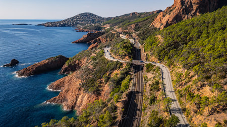 Panoramic aerial view of Esterel Mountains coastline with winding coastal road and railway tracks above the Mediterranean Sea, French Riviera, Southern France, scenic cliffs and ocの写真素材