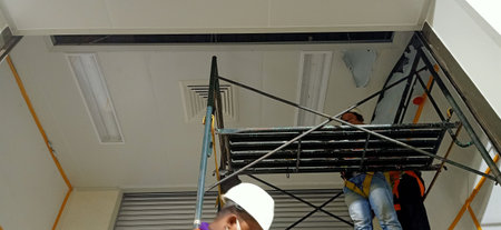 Worker installing scaffolding on the ceiling of a new house.の写真素材