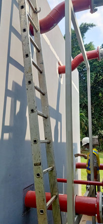 Ladder on a wall in a construction site with a worker.の写真素材